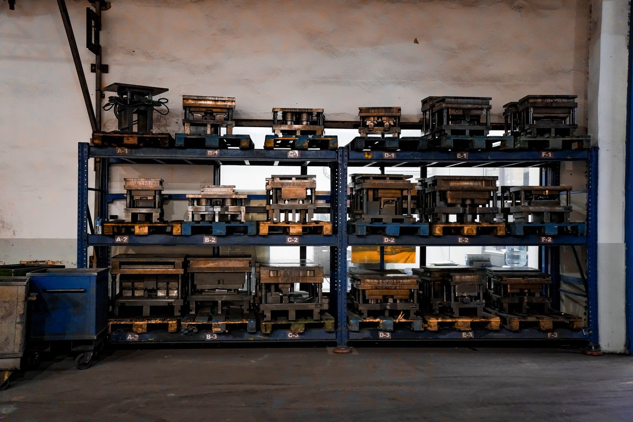 services-03 Metal molds neatly arranged on industrial shelving in a warehouse setting, showcasing order and efficiency.