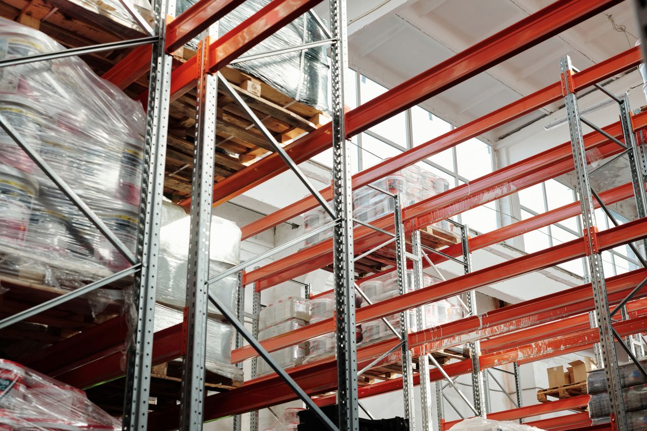 who-we-are Bright modern warehouse featuring pallets and storage racks for logistics and inventory management.